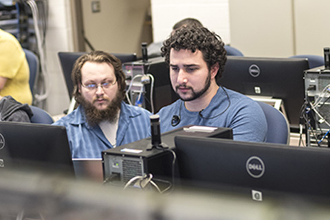 Cybersecurity instructor working with students in computer lab.