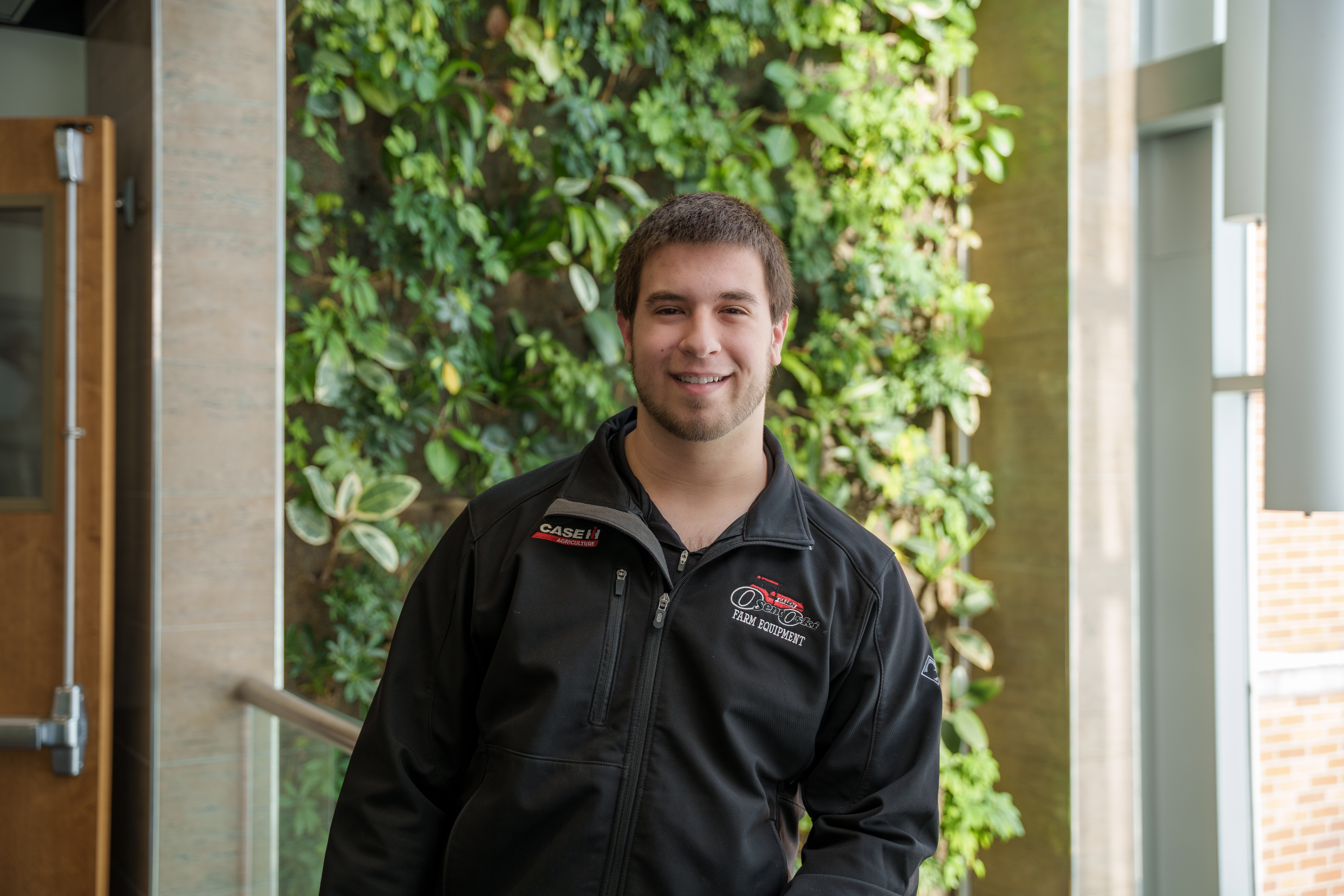 Noah Koth Delta College Agricultural Technology student poses in front of campus living wall