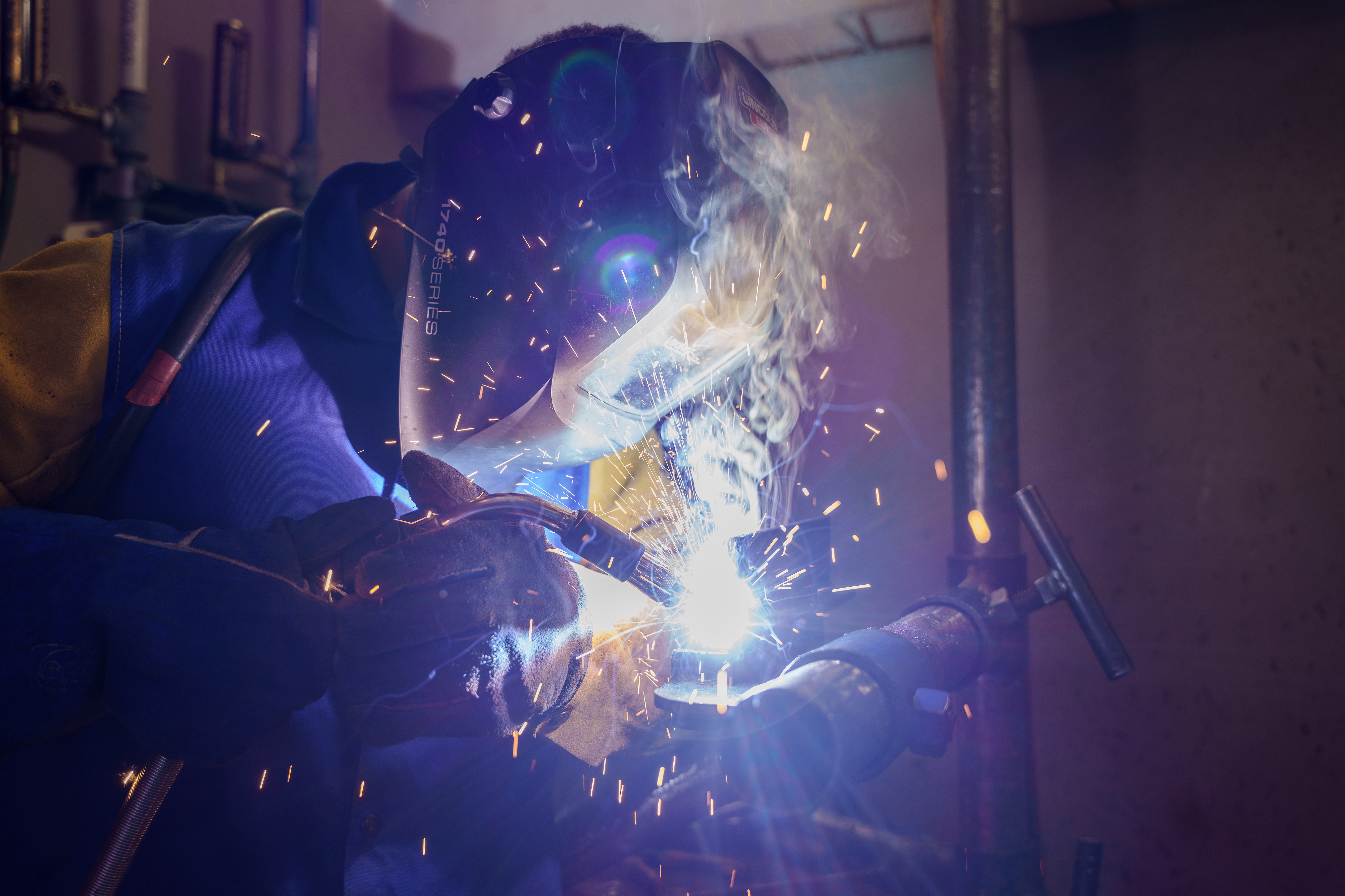 Delta College Welding student wearing face helmet and making sparks fly
