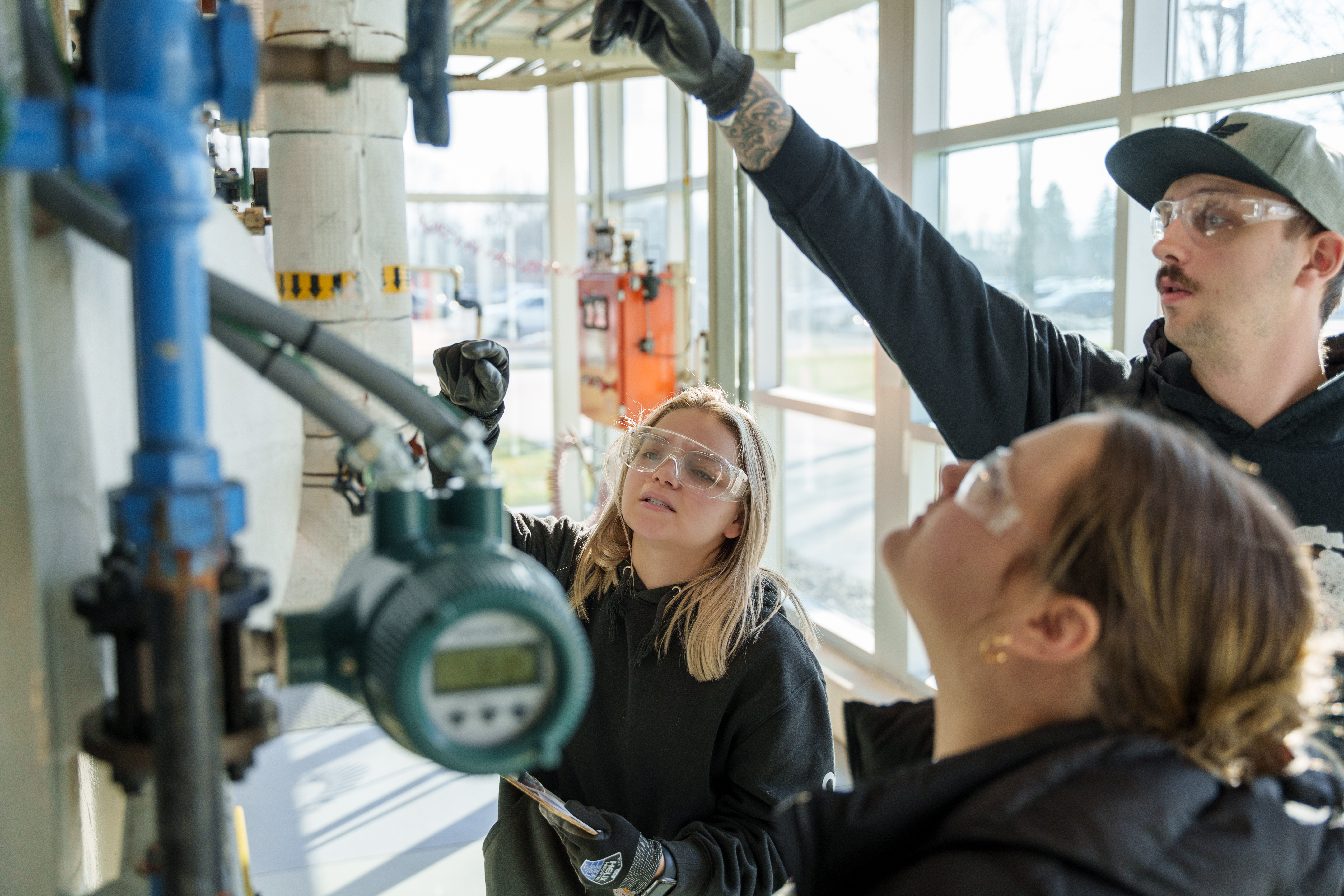 Three students, two female-presenting and one male-presenting, work together in Delta's chemical processing lab