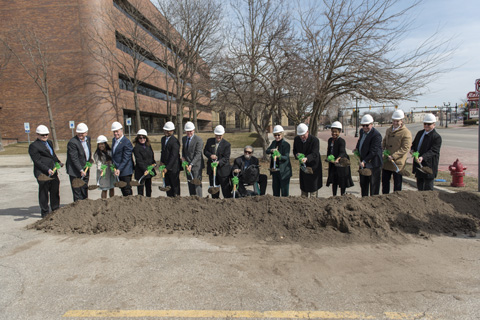 A group of local administrators at the site of the new Saginaw Center wearing hard hats and holding shovels. 