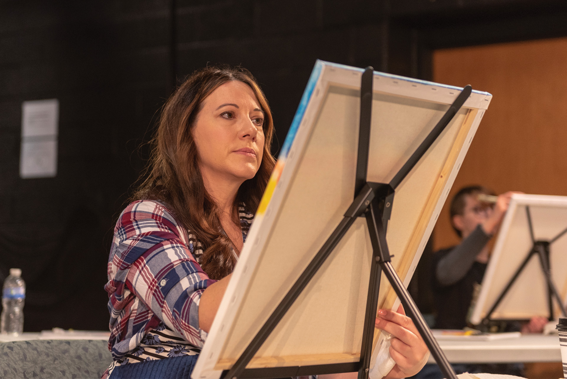A woman painting at the Bob Ross Workshop