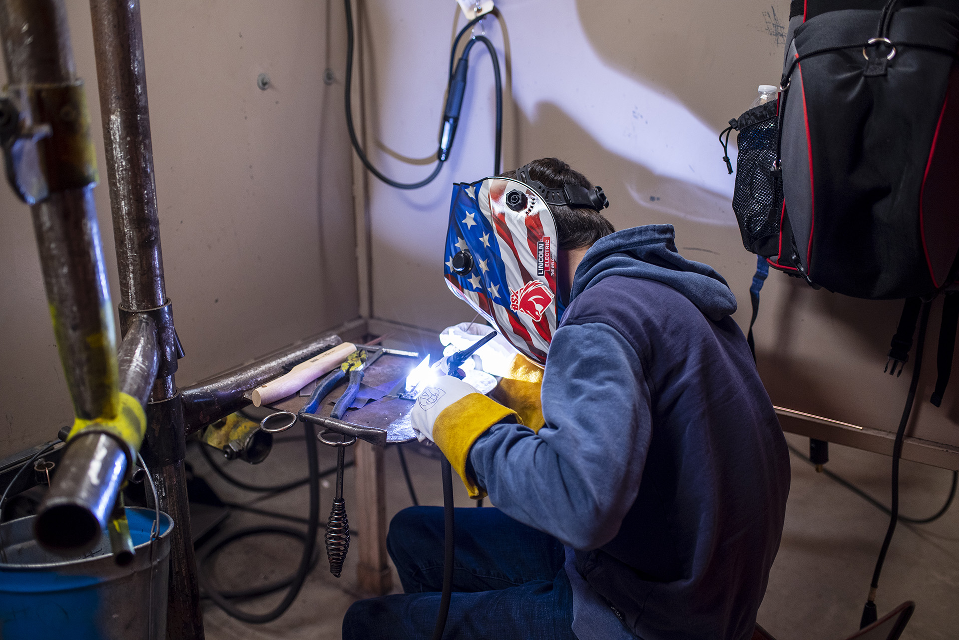 Outfitted in his protective mask, a student fine tunes his welding skills.