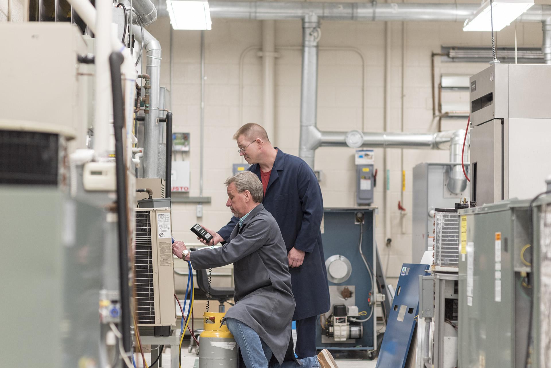 A student and professor work together in the HVAC lab.