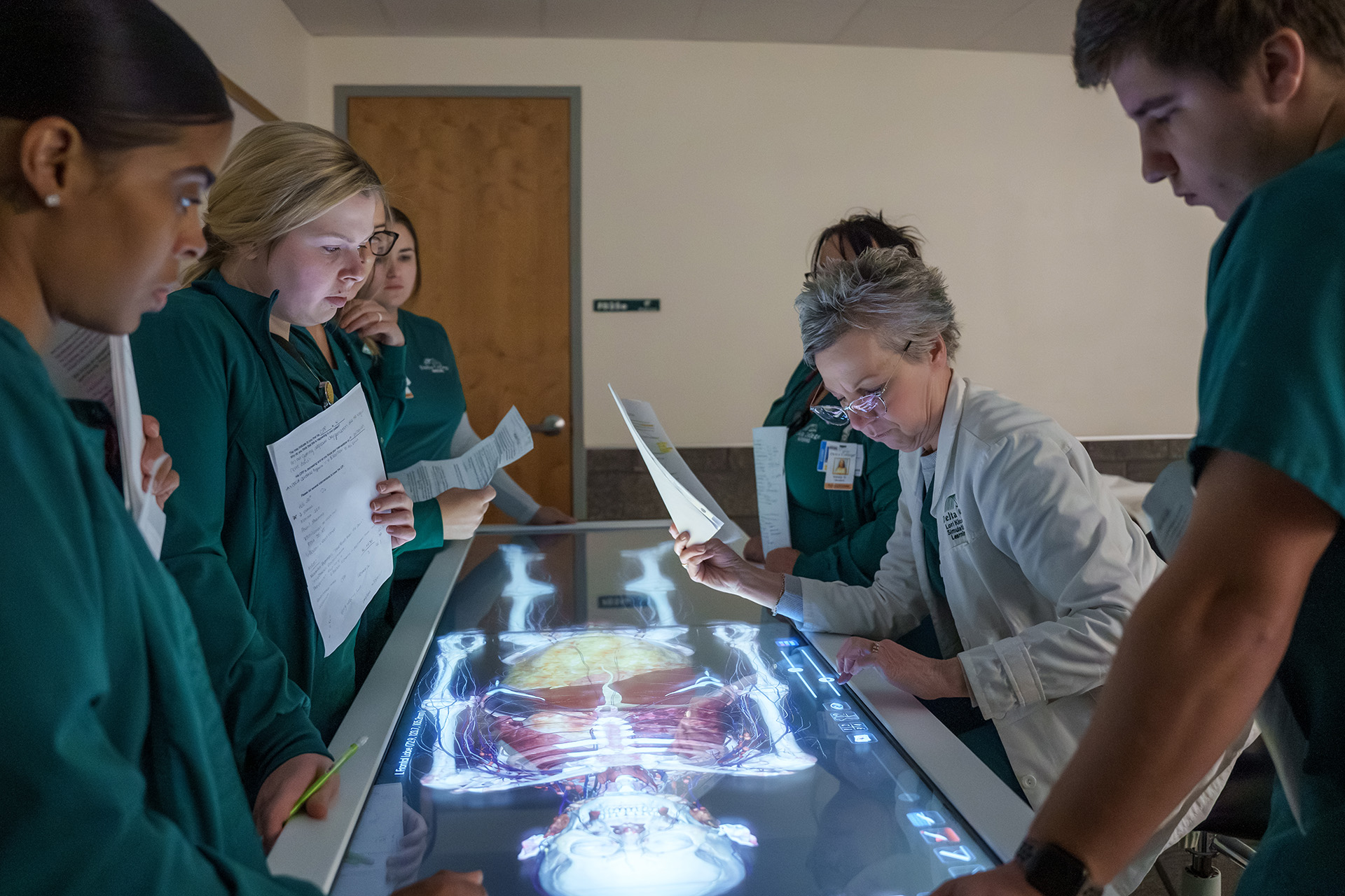 Students standing around anatomage table.